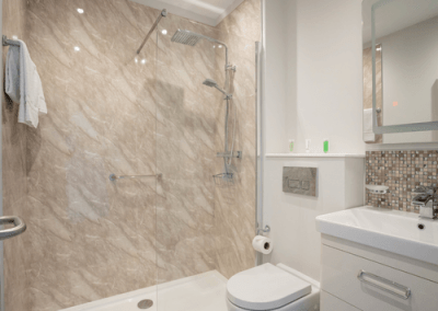 Bright, modern en-suite bathroom with walk-in shower, grab rails, toilet and vanity unit.
