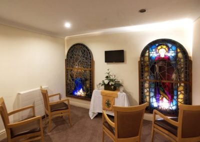 Peaceful chapel-style room with stained glass windows and seating for quiet reflection or small services.