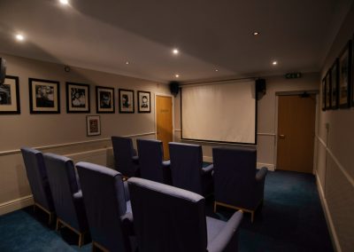 Private cinema room with projector screen and comfortable high-backed seating for film viewings.