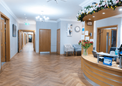 Bright and modern reception area with wooden flooring, curved desk and comfortable seating.