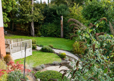 Well-maintained garden with curved pathways, lawn, shrubs and mature trees creating a tranquil outdoor space.
