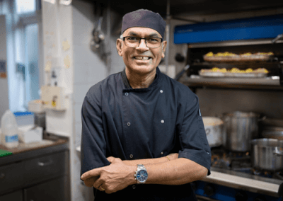 Head chef standing in a professional kitchen, preparing freshly cooked meals for residents.