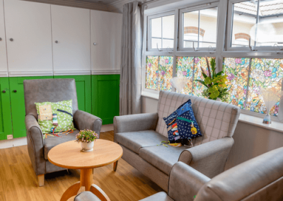 Comfortable quiet lounge with armchairs, sofa, coffee table and large windows providing natural light.