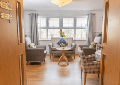 Comfortable quiet lounge with armchairs, sofa, coffee table and large windows providing natural light.